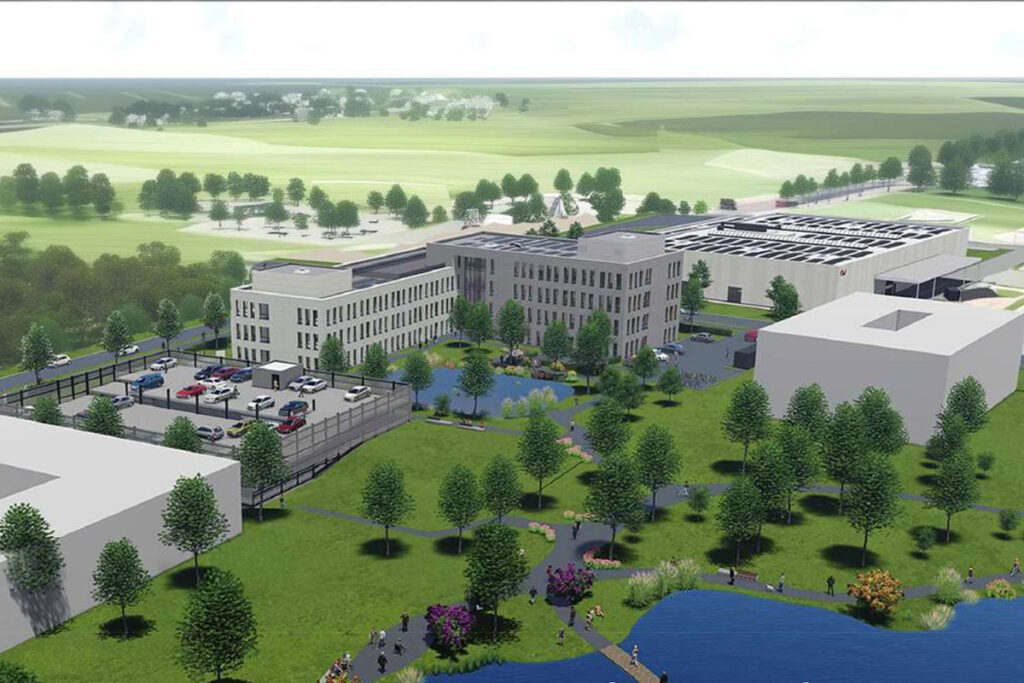 Luftaufnahme eines modernen Bürokomplexes mit Parkplatz, umliegenden Bäumen, Grünflächen und einem Teich im Vordergrund.