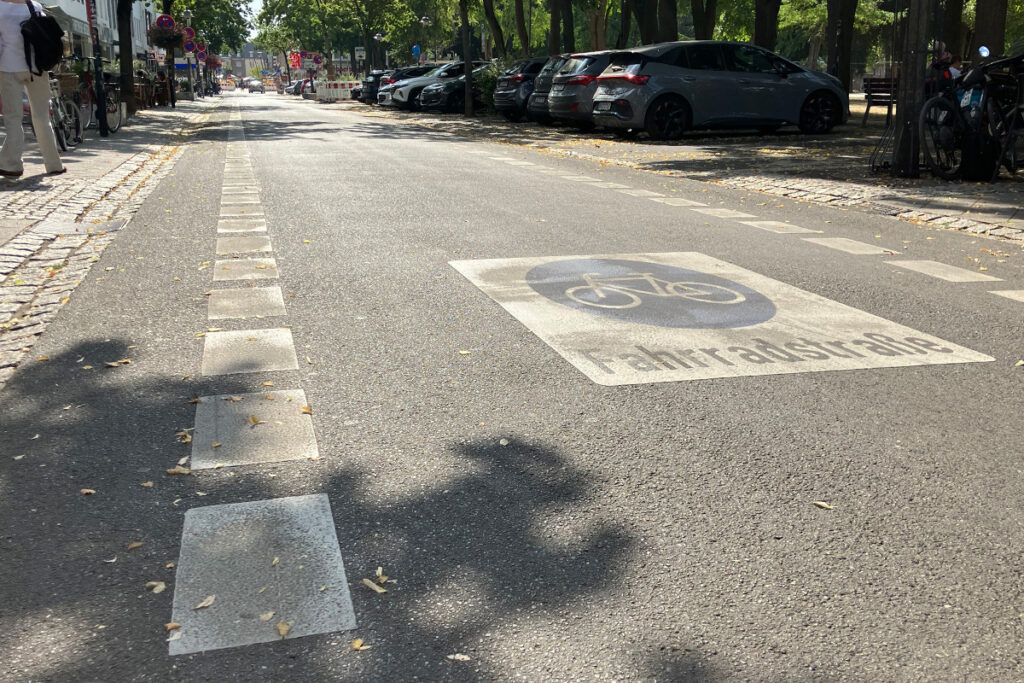 Eine Straße mit einer Fahrradstreifenmarkierung und der Aufschrift Fahrradstraße auf dem Asphalt.