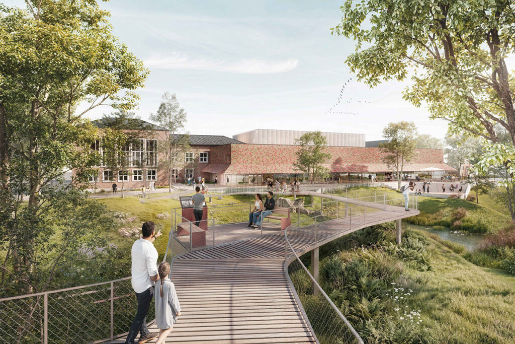 Architekturvisualisierung eines Parks mit einer Holzbrücke, die zu einem modernen Gebäudekomplex mit Backstein- und gemusterten Fassaden führt.